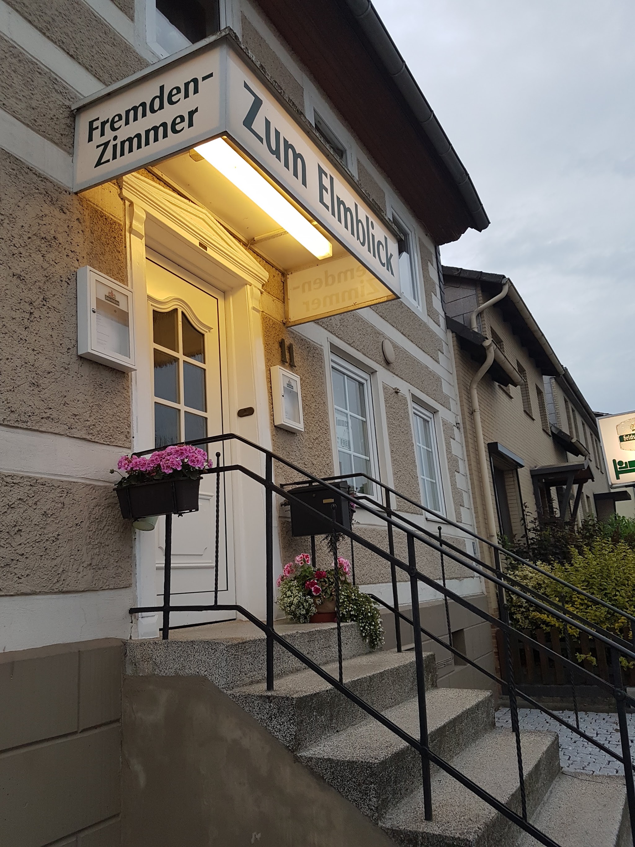 Eingang des Gasthofs Zum Elmblick mit dem Schild Fremden-Zimmer und Blumenkästen